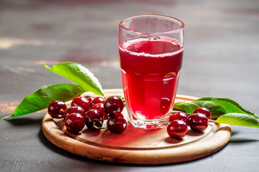 Glass of sour cherry juice with fresh red cherries